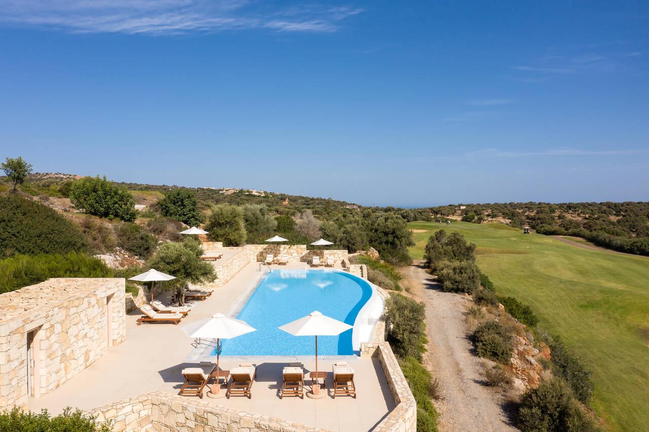 Overhead view of the outdoor swimming pool at the resort with sunbeds overlooking the course