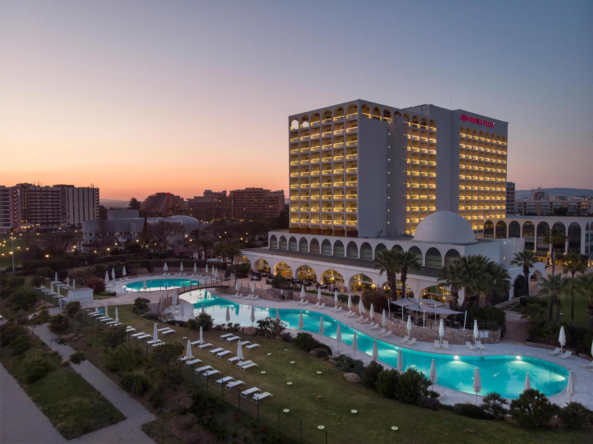 Outside view of the Crowne Plaza Vilamoura at dusk with swimming pool visible