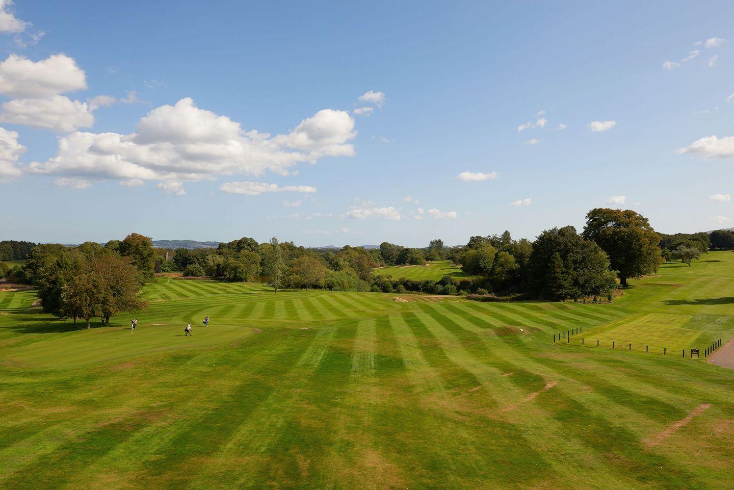 A wide view of the Dalmahoy West Course fairways with golfers enjoying a sunny day.