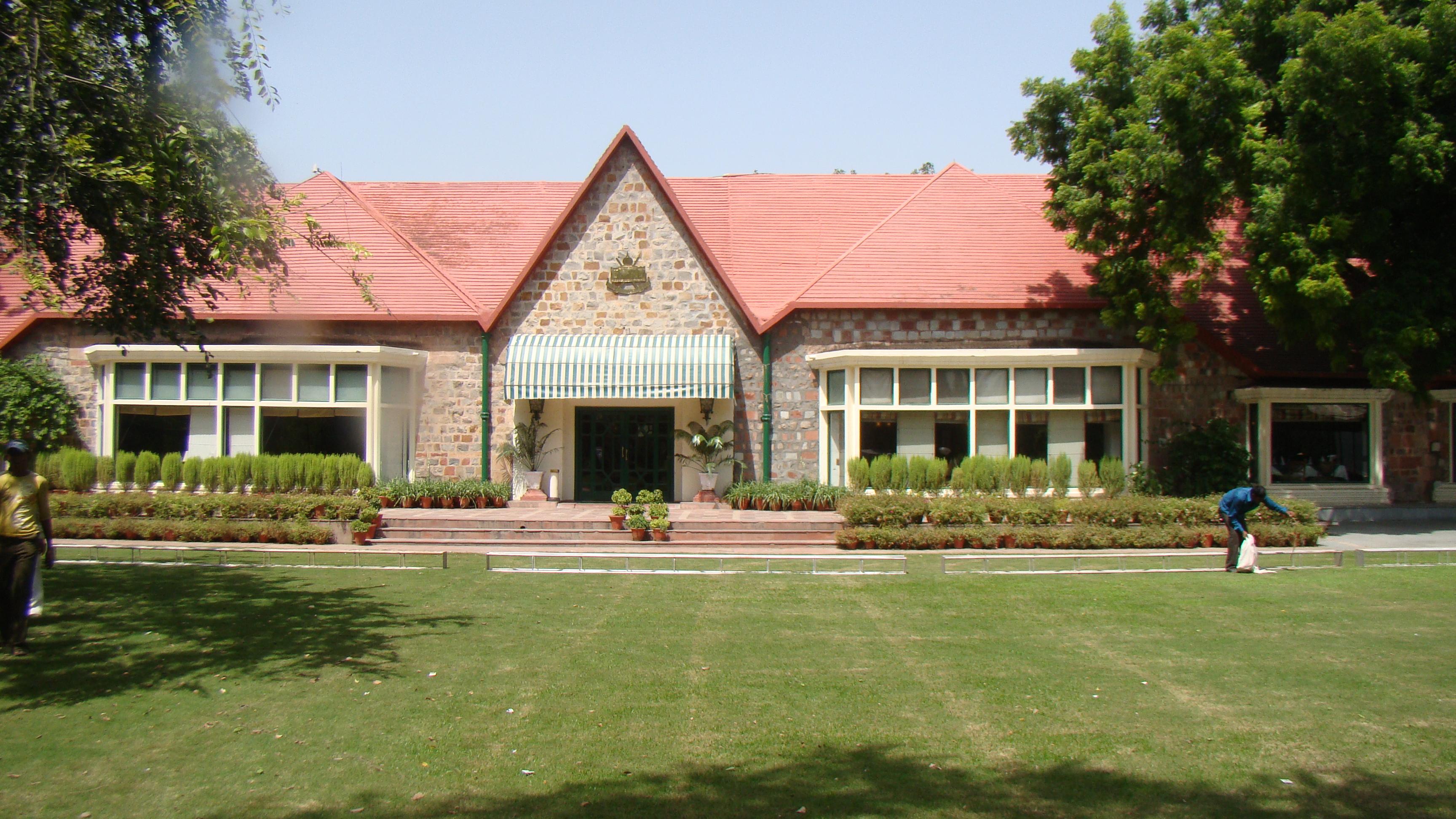 A traditional stone clubhouse with red roofing and manicured lawns.