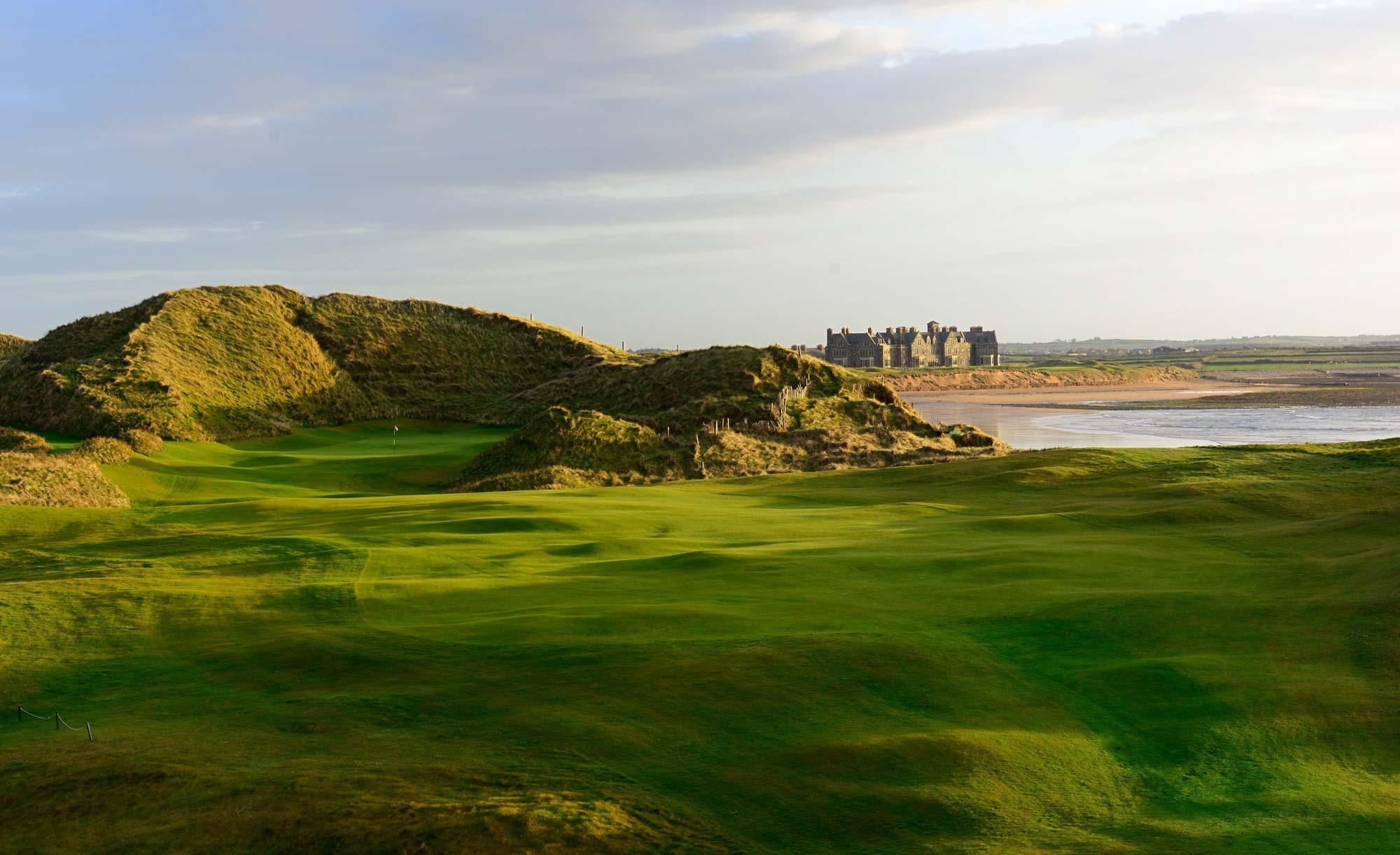Rolling green fairways with the resort in the distance by the beach.