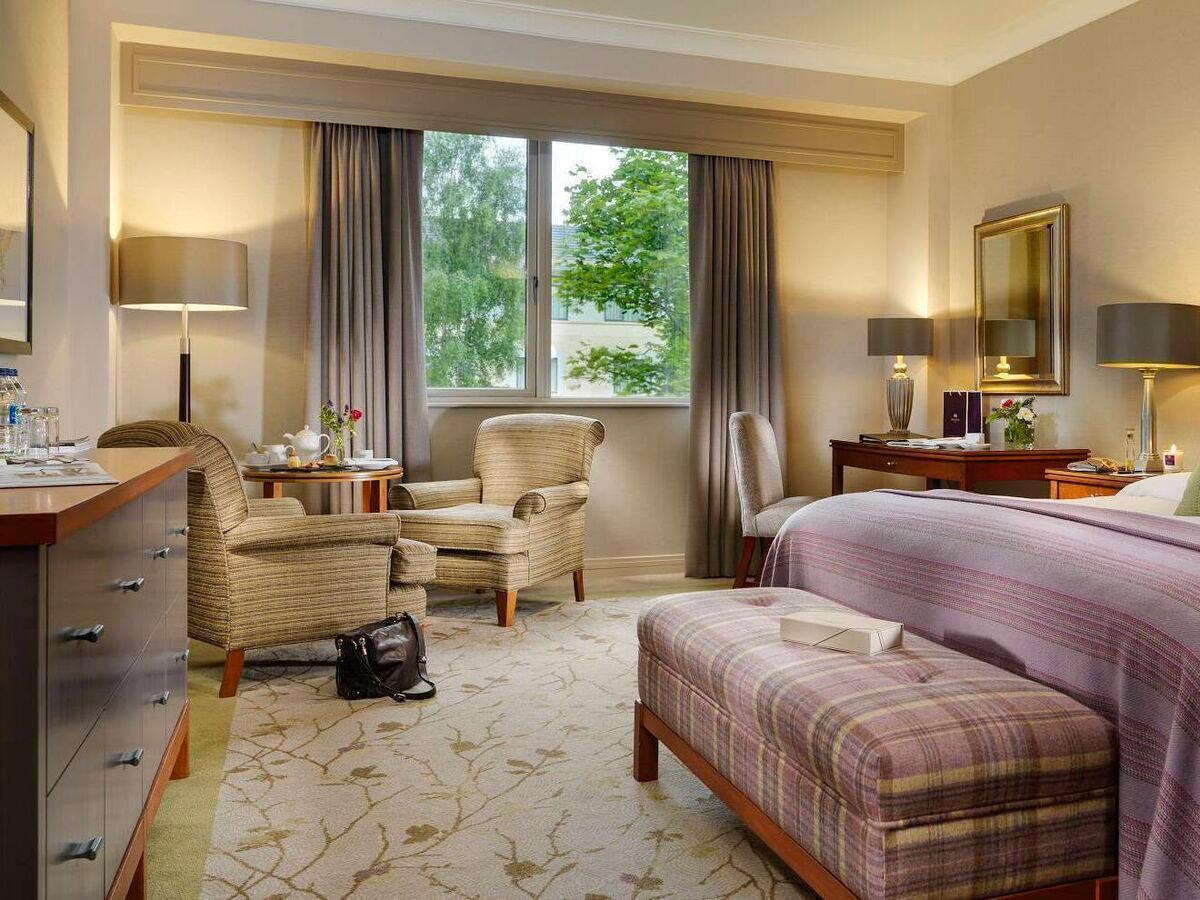 Elegant hotel room with cozy seating and natural light.