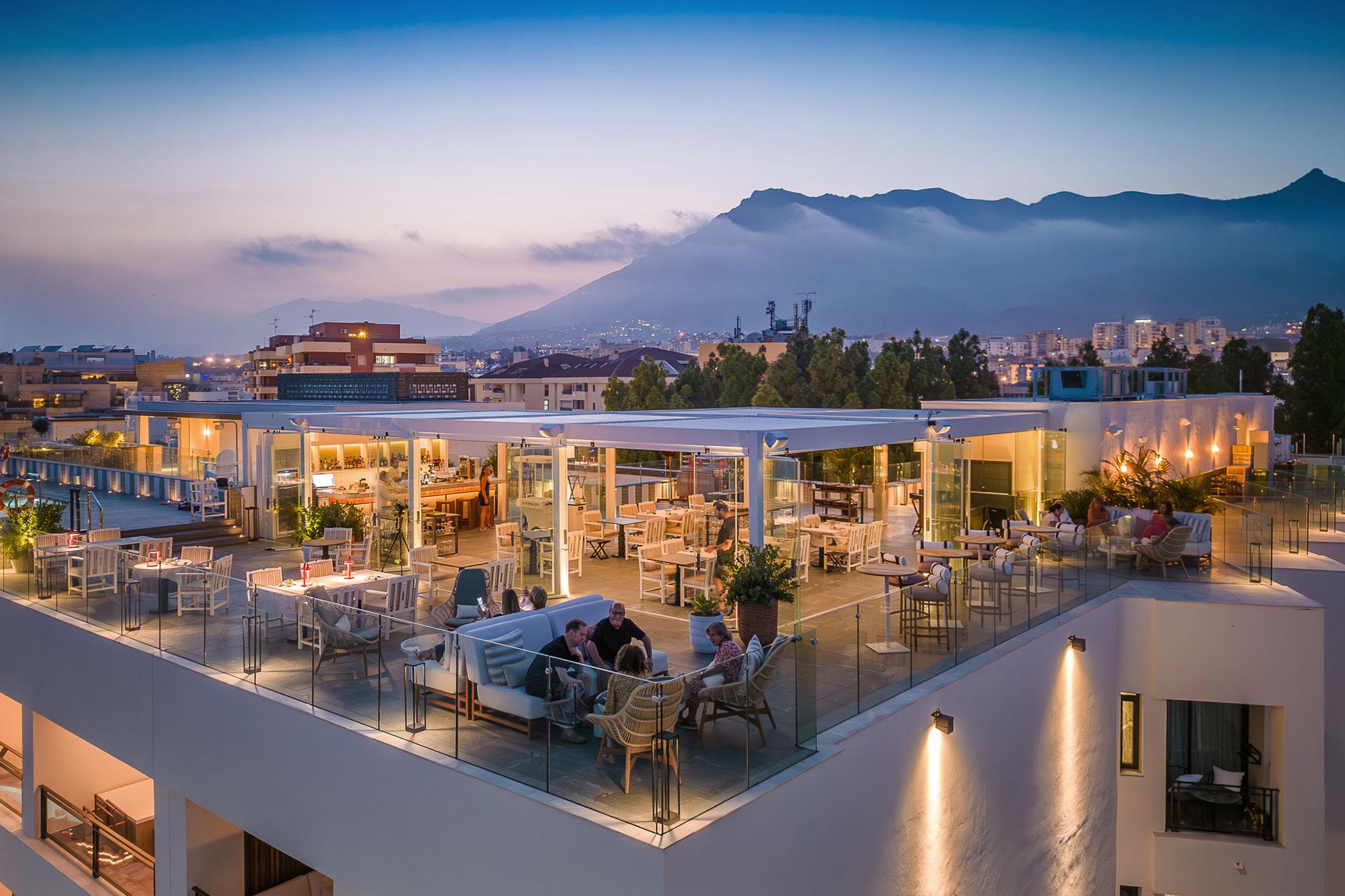 Rooftop bar area at dusk with mountains in the background