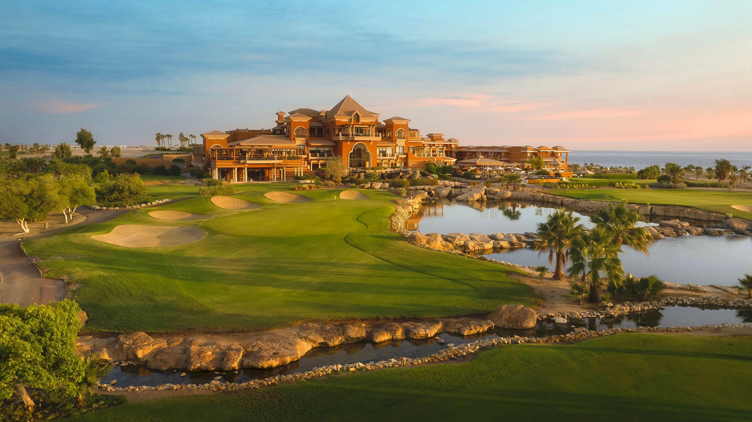 A luxurious clubhouse overlooking pristine greens and reflective water features.