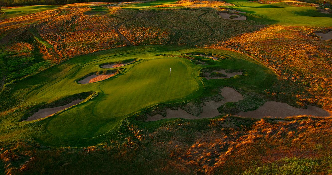 Birdseye view of an elevated green surrounded by sand bunkers and a yellow rough