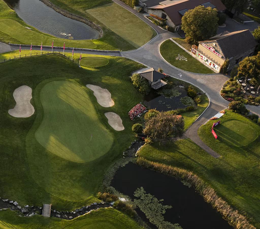 Bird's eye view of a green with bunkers around and water in front