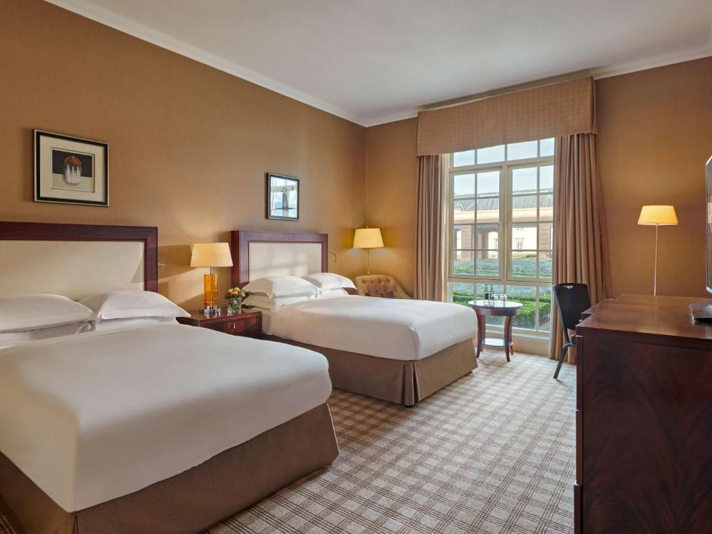 A comfortable and elegant twin hotel room with large windows offering natural light.