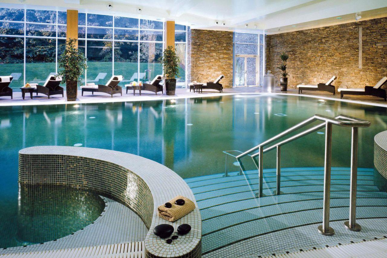 Indoor spa pool with loungers and large windows.