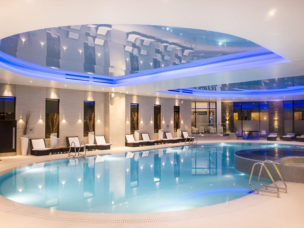Luxurious swimming pool and jacuzzi at the Gleneagles resort with blue lights illuminating the spa area