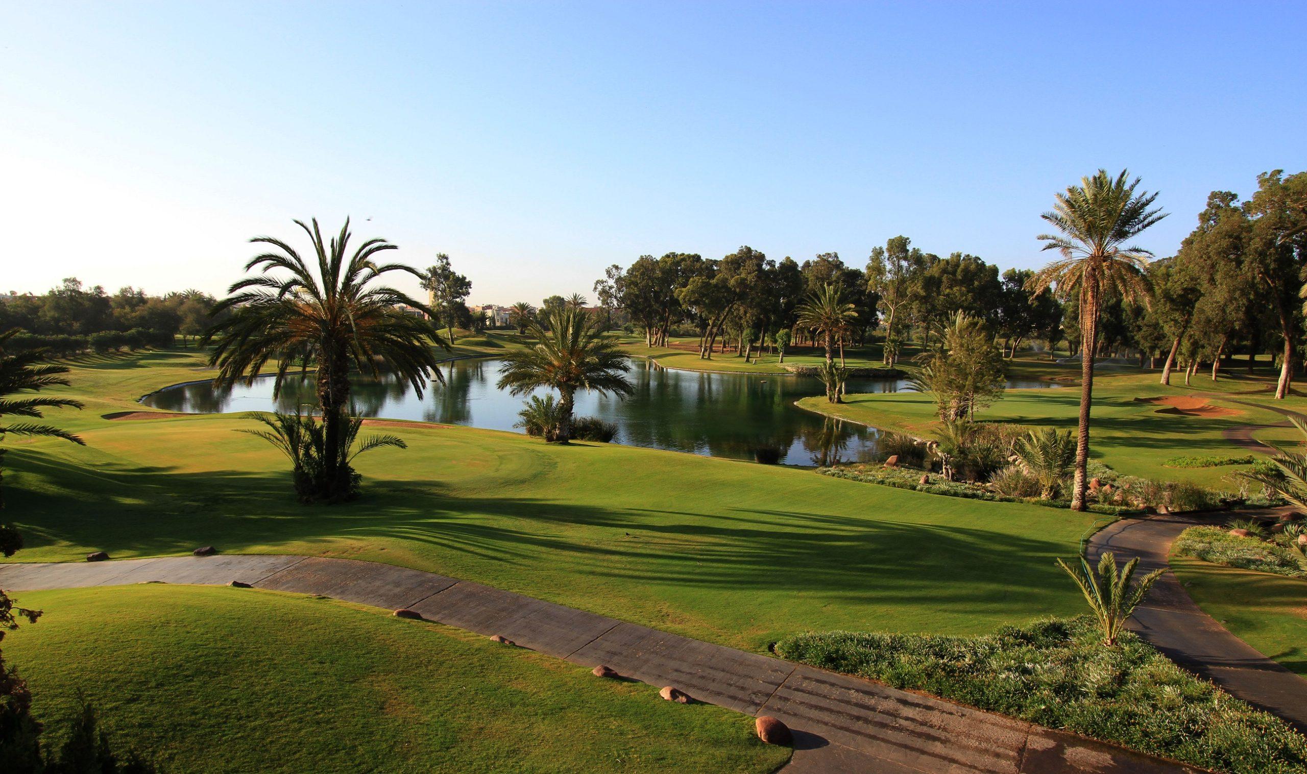 A calm pond surrounded by well maintained fairways nestled with palm trees