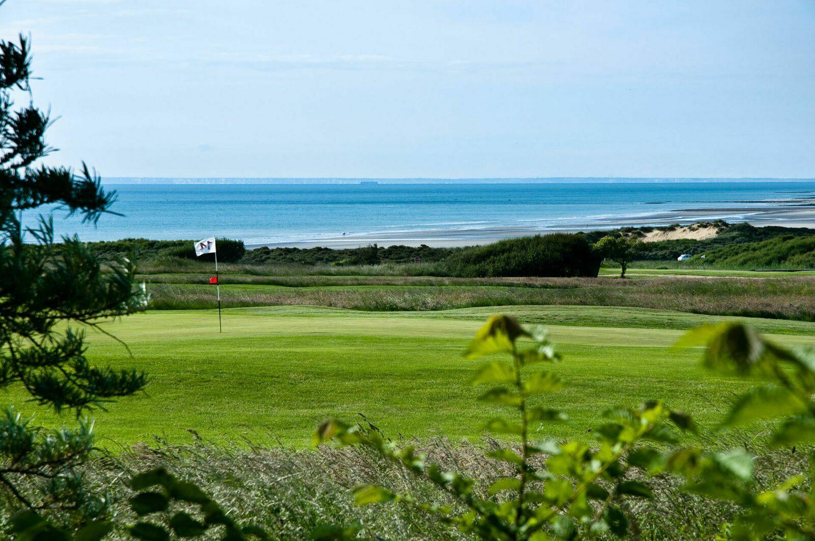 Manicured fairway, rough and green with the ocean in the background