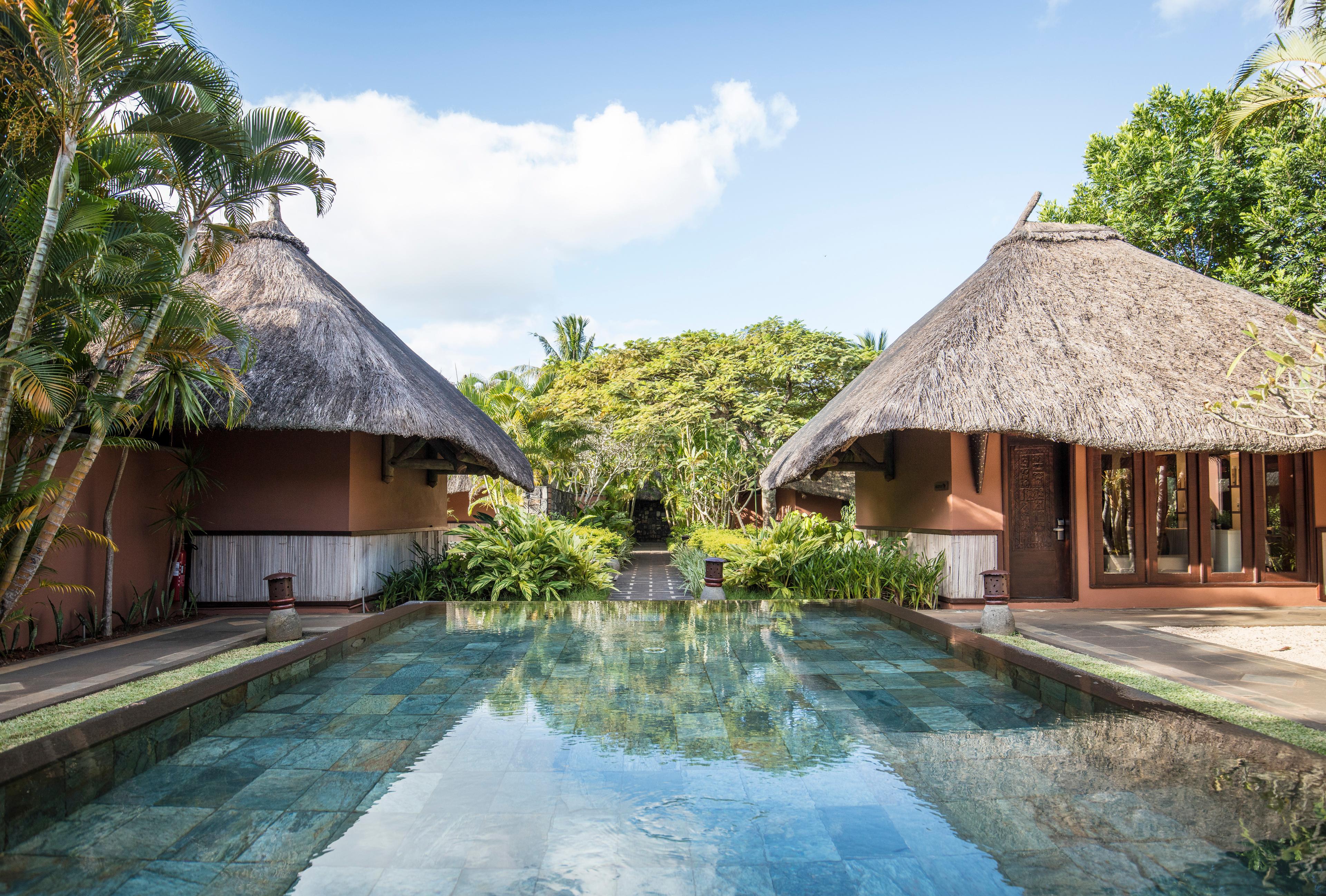 An outdoor swimming pool at the end of a jungle framed walk way