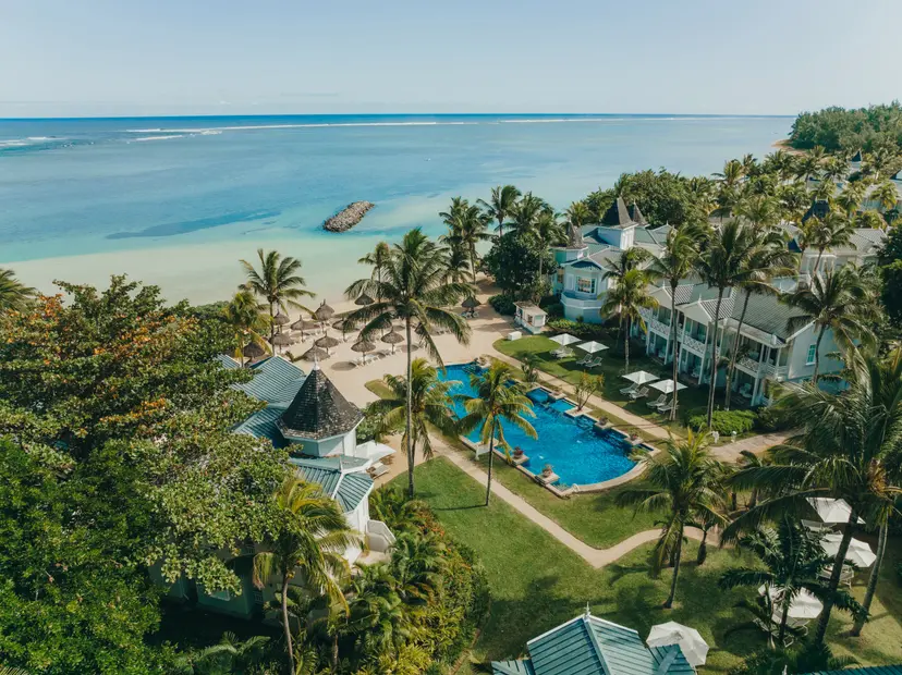 Birdseye view of the outdoor swimming pool leading to the beach under clear blue skies