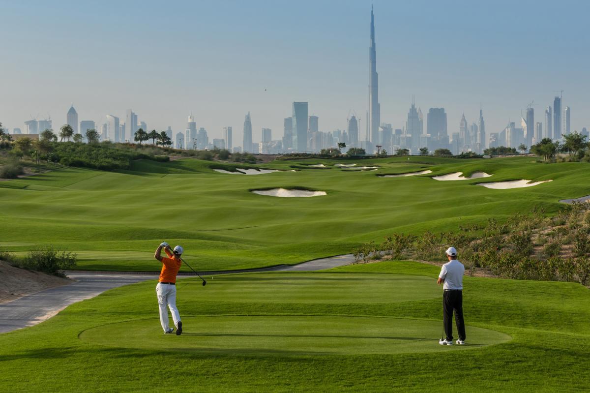 Two golfers walking on a fairway with skyline view