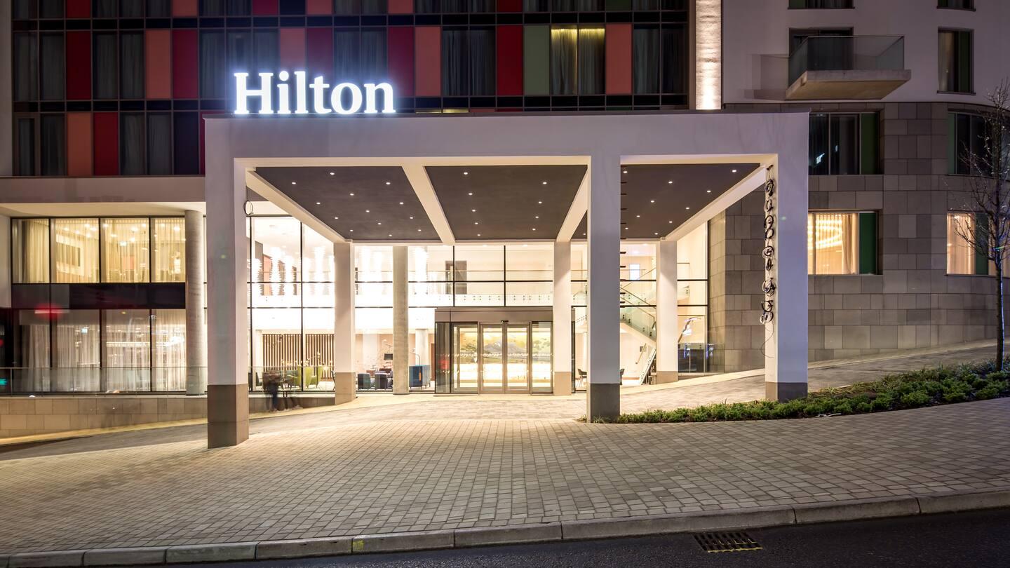 Front entrance to the Hilton with large pillars separating the road from drop off point