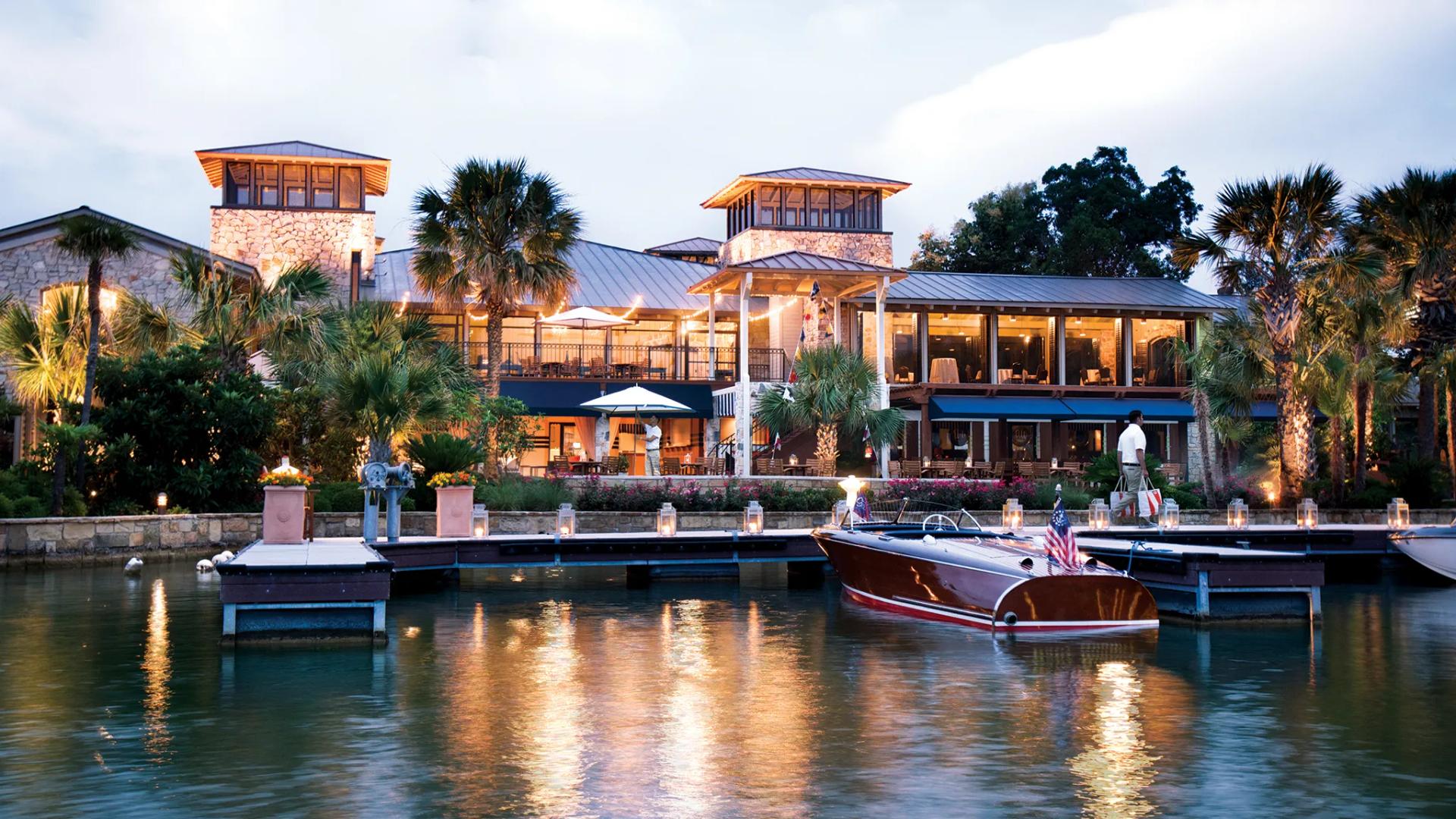 A stunning waterfront view of Horseshoe Bay Resort with boats docked along the serene lake at dusk.