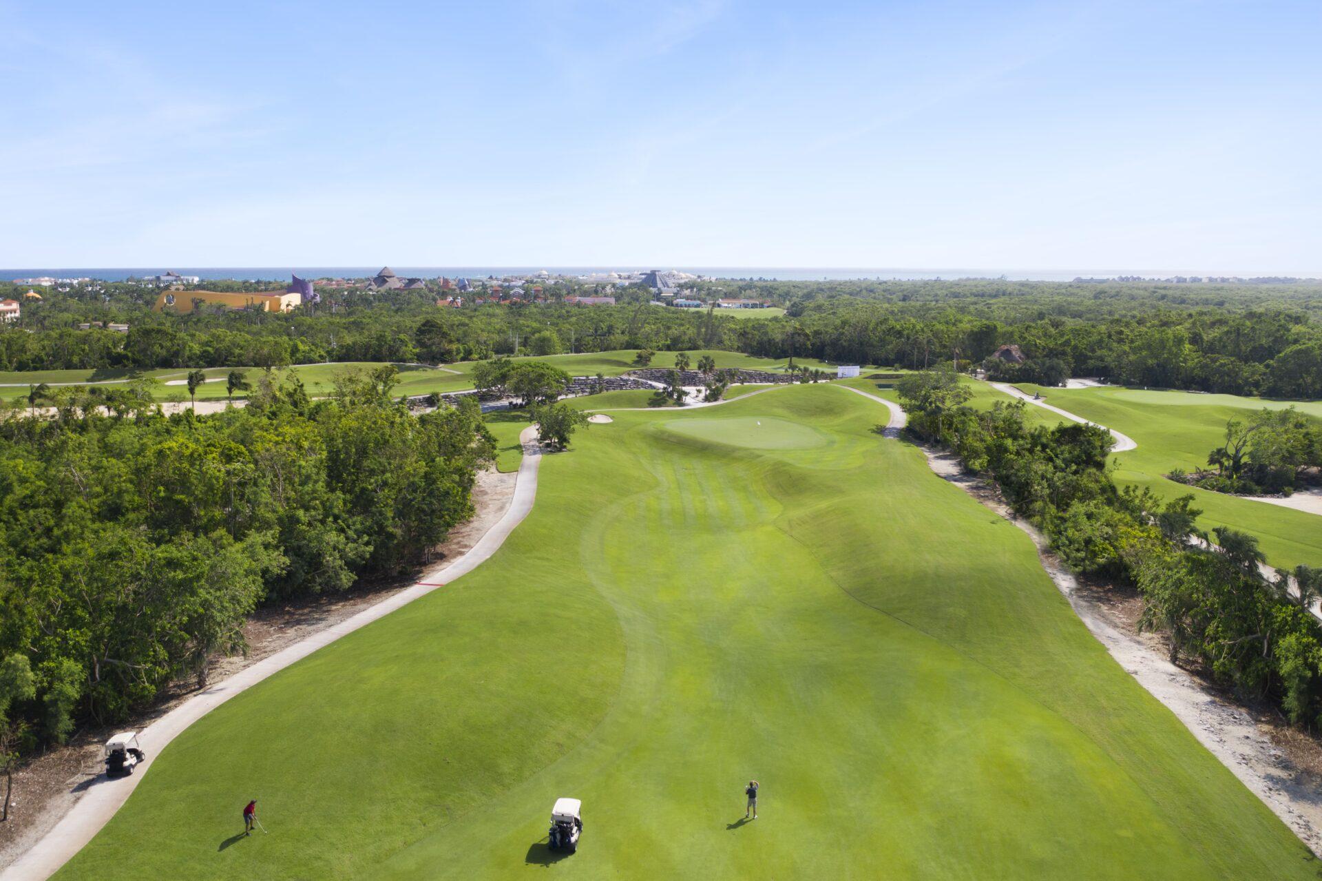 Golfers enjoying their round of golf on a wide fairway leading to a smooth green