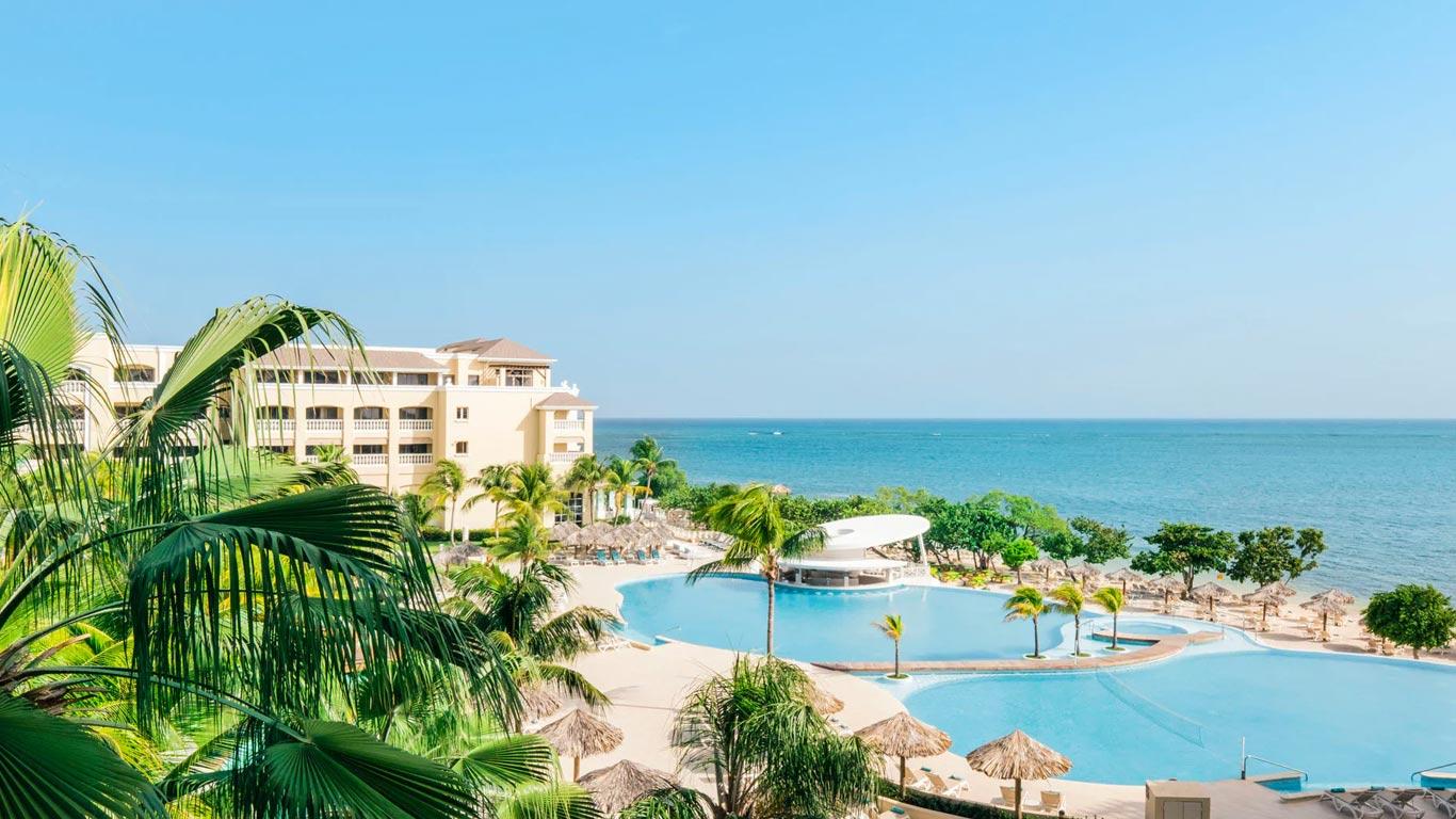 Palm trees surrounding the outdoor swimming pool with easy access to the beach