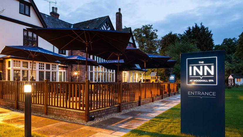 Outdoor seating area at The Inn with its company logo illuminated on the entrance sign