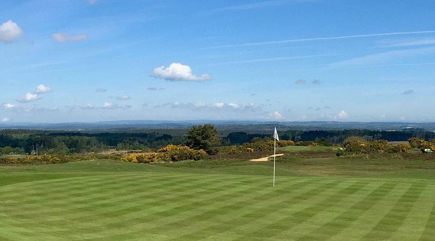 Flagstick on the well-maintained green under blue skies
