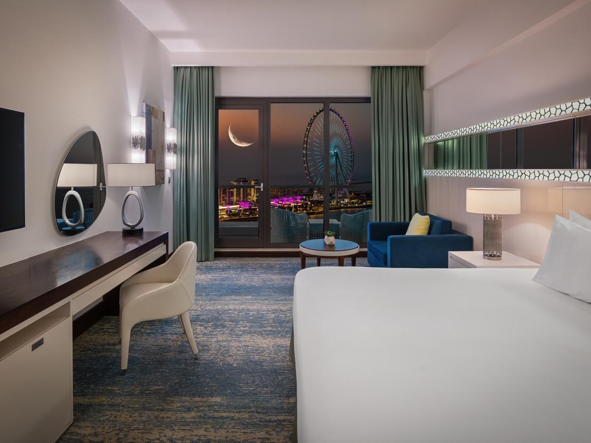 A double bed room with balcony views of a ferris wheel and quarter moon