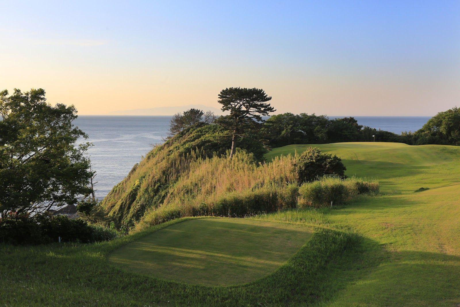 Cliffside green overlooking the ocean at sunset.