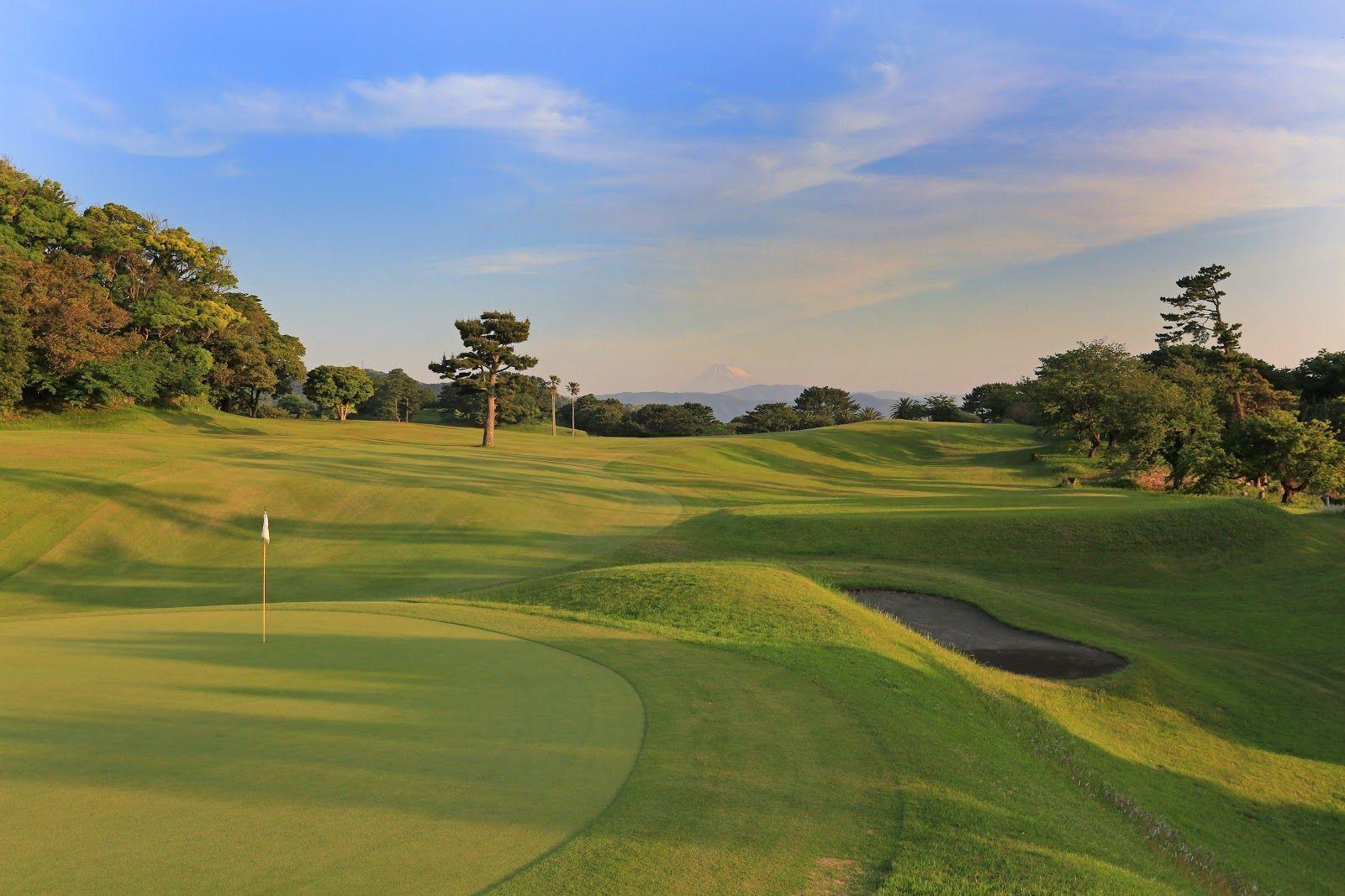 Rolling fairways with a flagstick and distant mountain views.