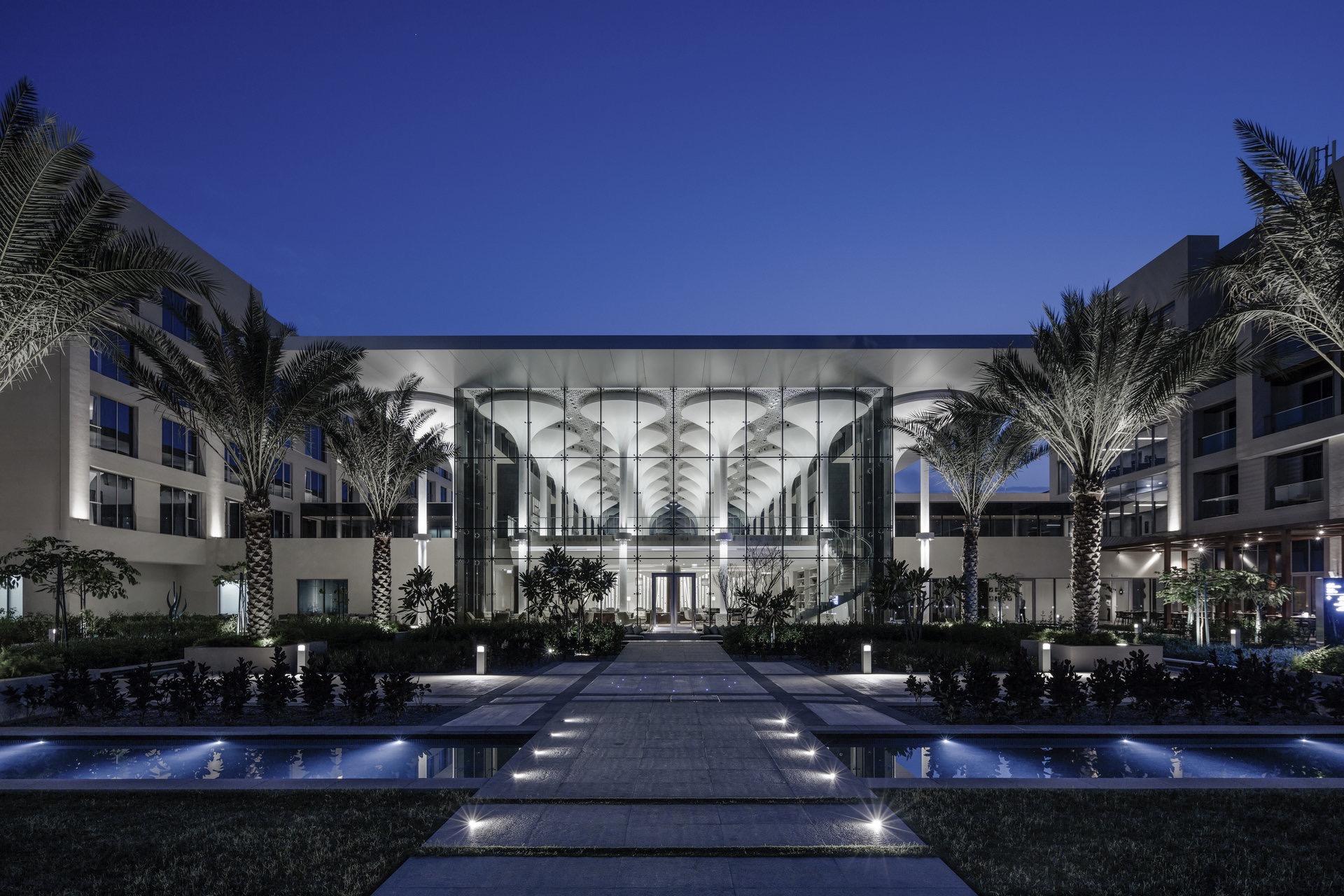 An exterior view of the Kempinski Hotel Muscat building being lit up at night time