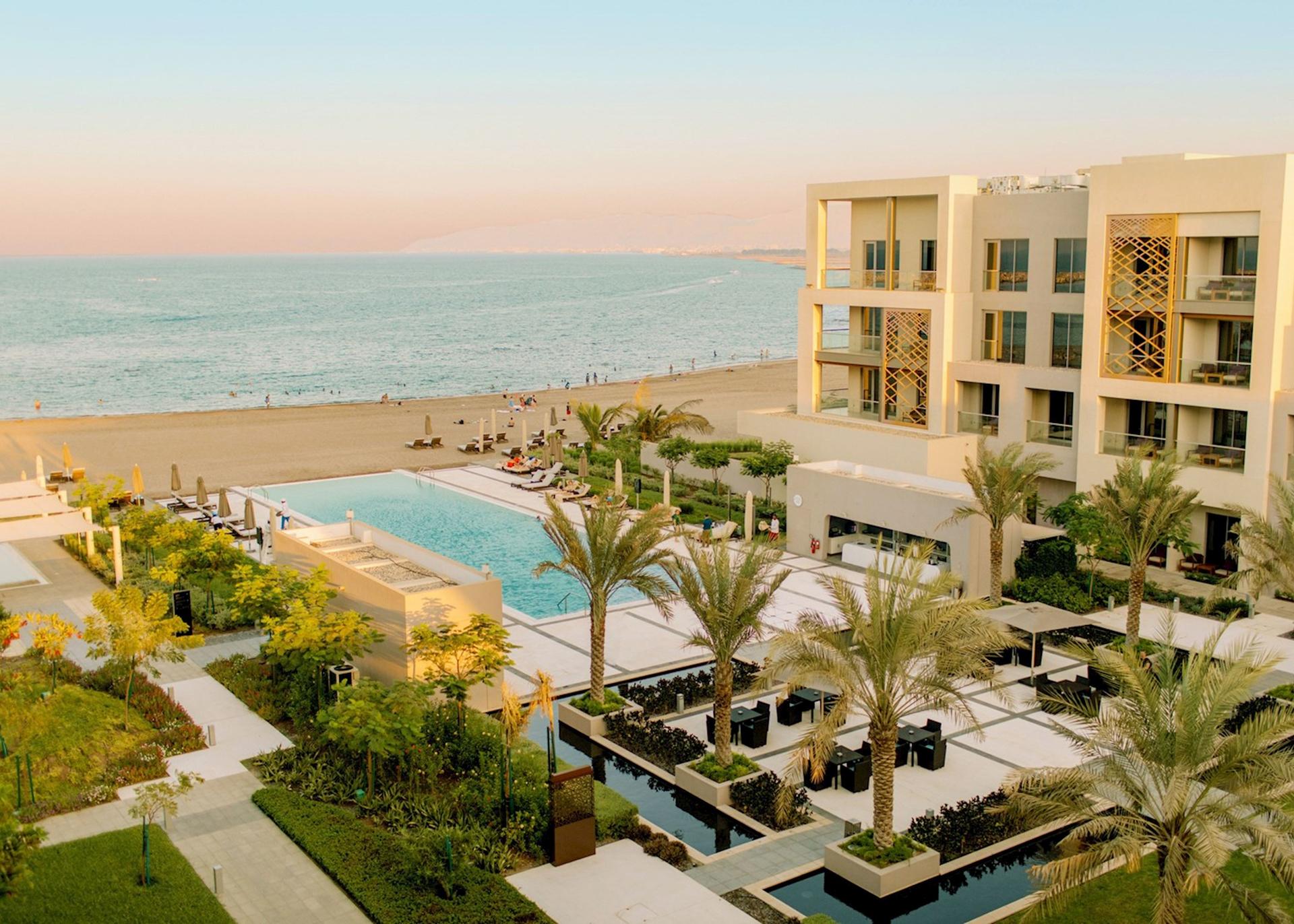 An outdoor swimming pool nestled with palm trees at the hotel leading to the beach