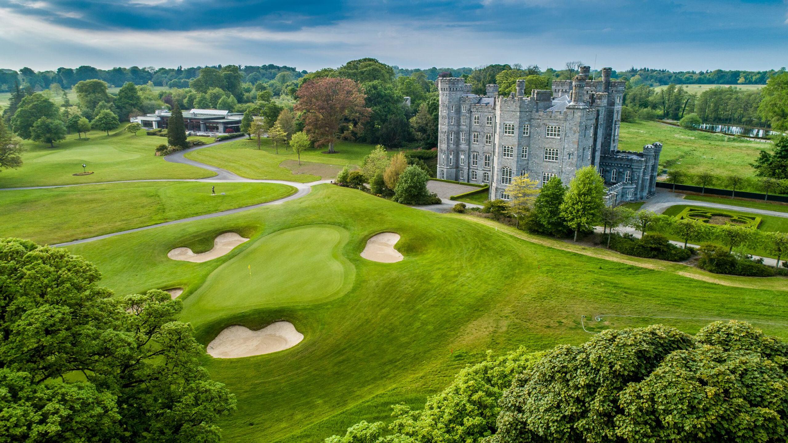Aerial view of a castle surrounded by pristine fairways.