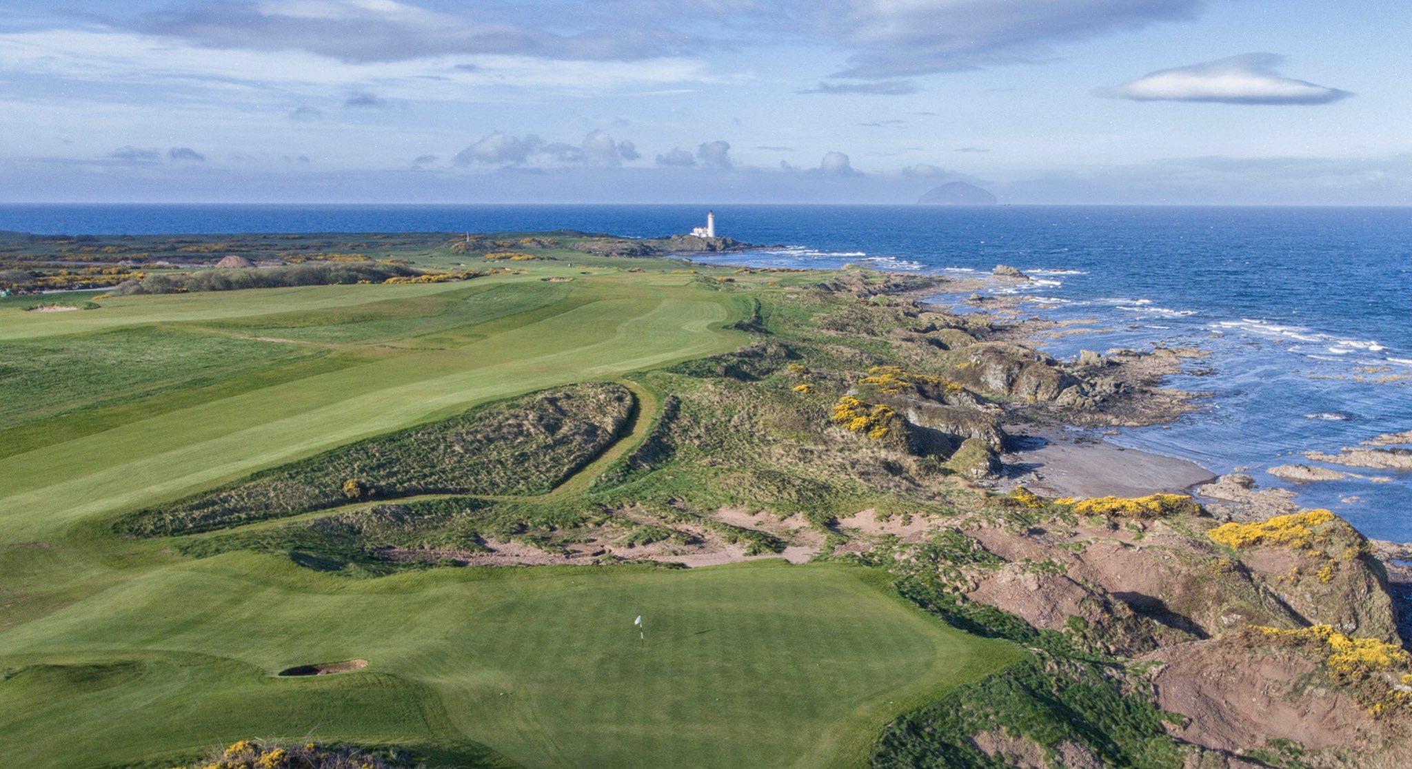 Aerial shot of wide fairways running down the rugged stone coast