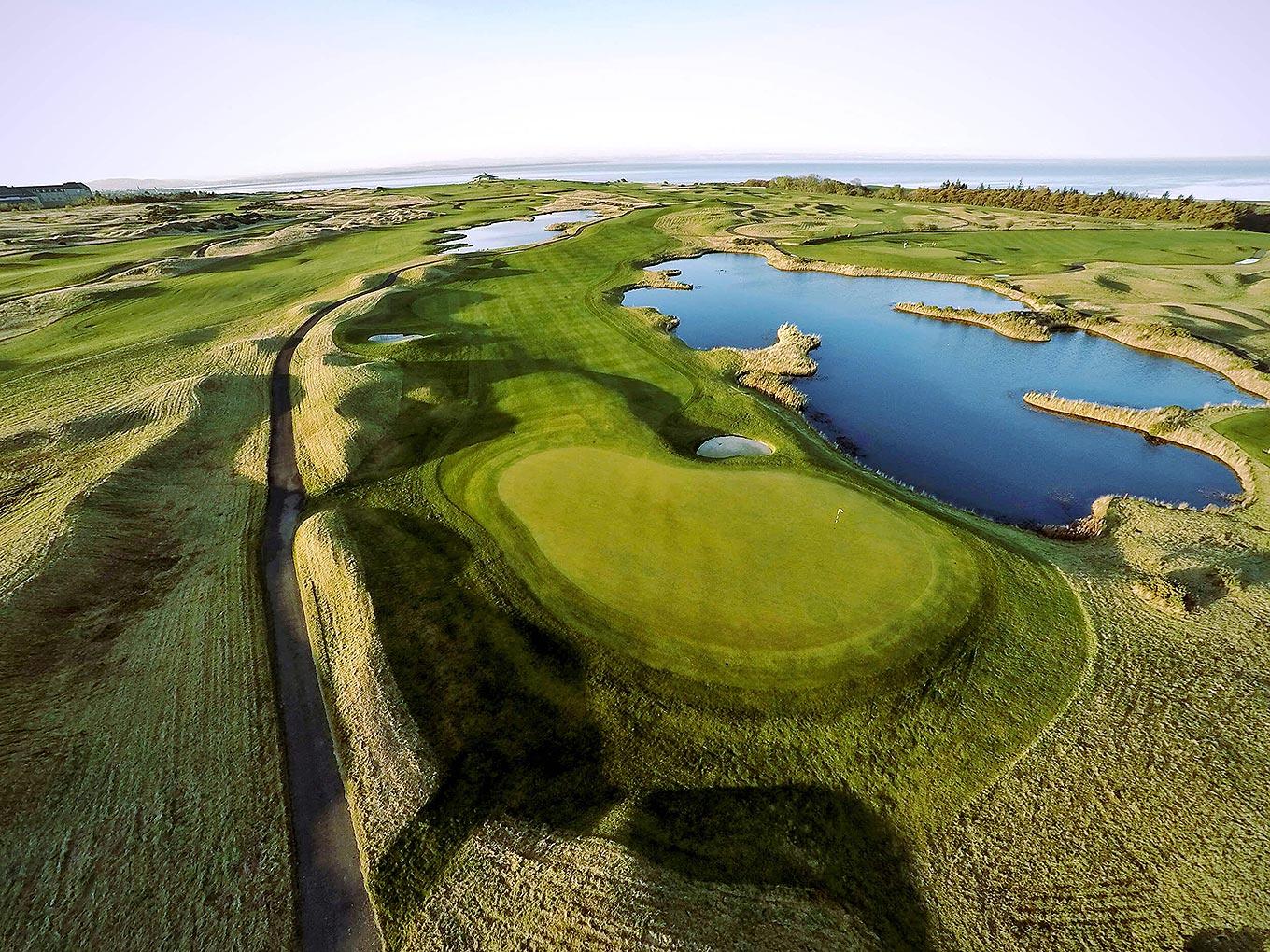 A championship hole winds around a large water hazard with rolling fairways.
