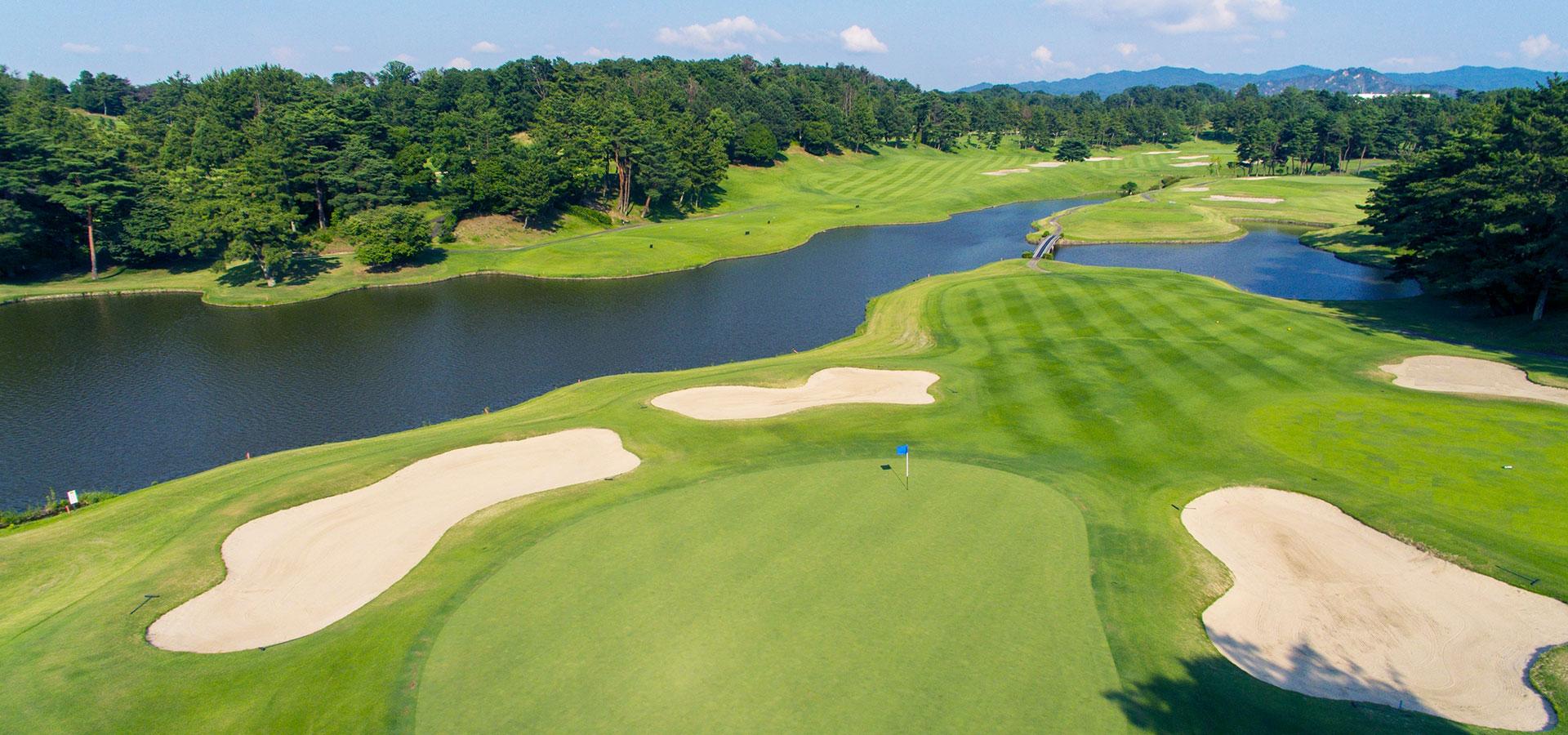 A stunning lakeside hole with sand traps and rolling fairways surrounded by forest.