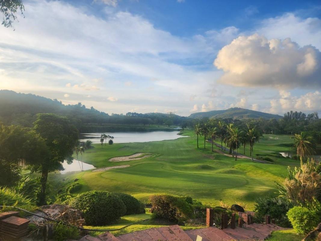 Rolling green fairways stretch toward a distant mountain backdrop.