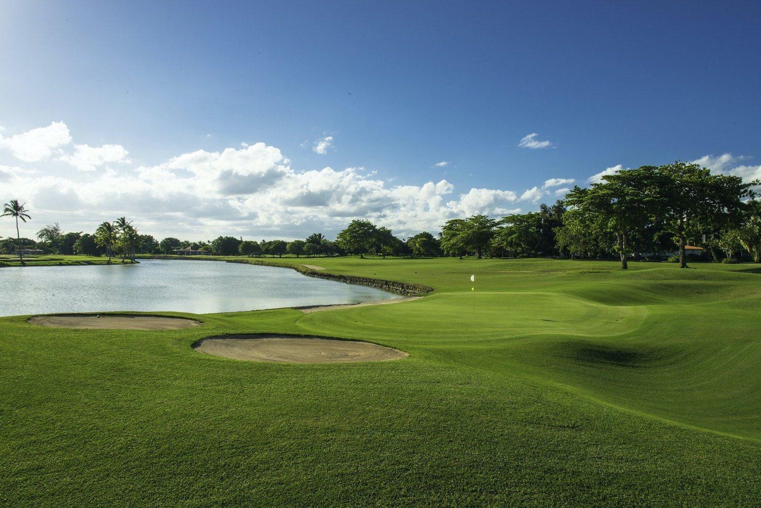 A smooth green placed next to a sand bunkers with a river running through the course