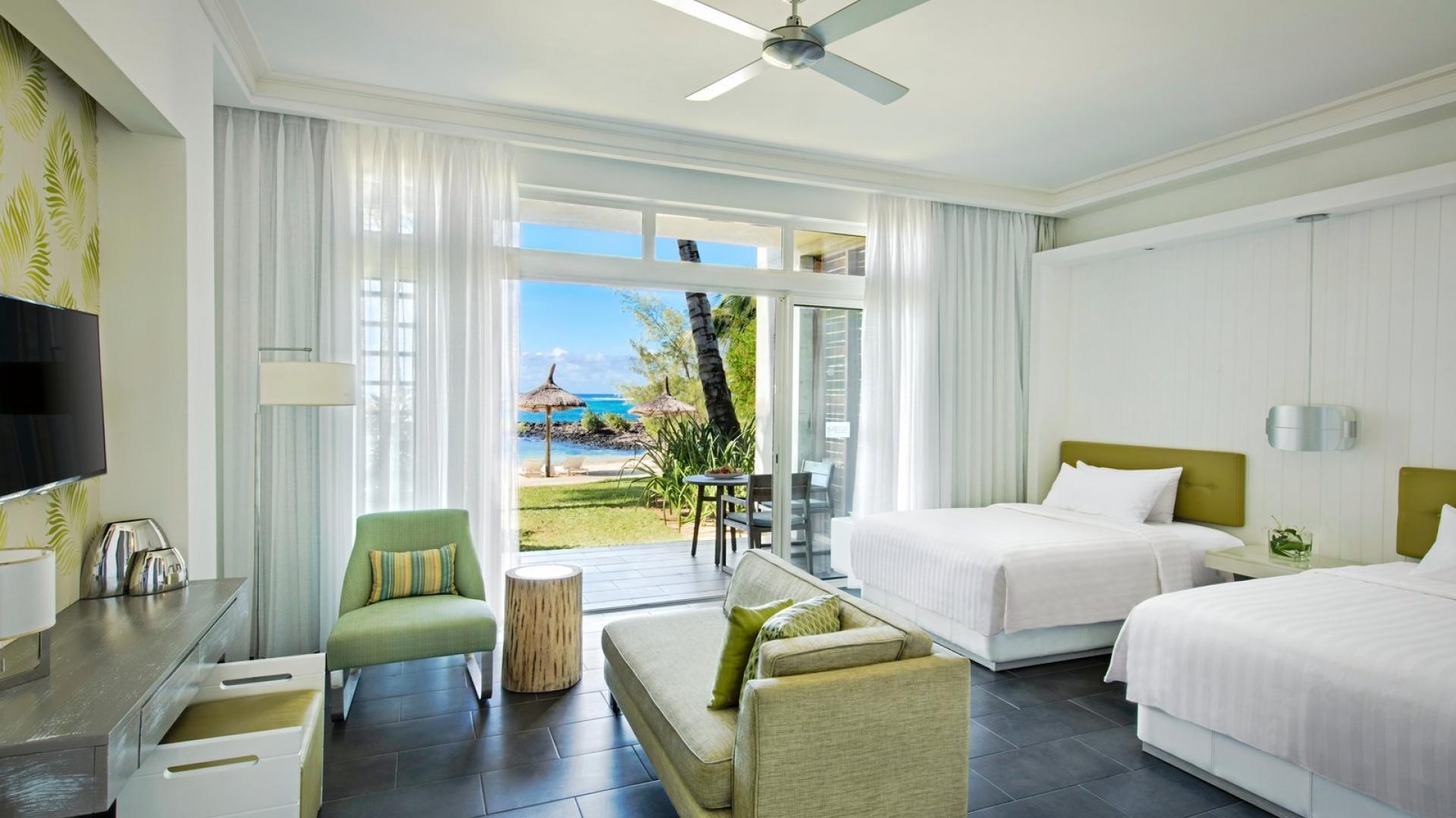 A spacious twin double bed room with a patio that leads out to the beach