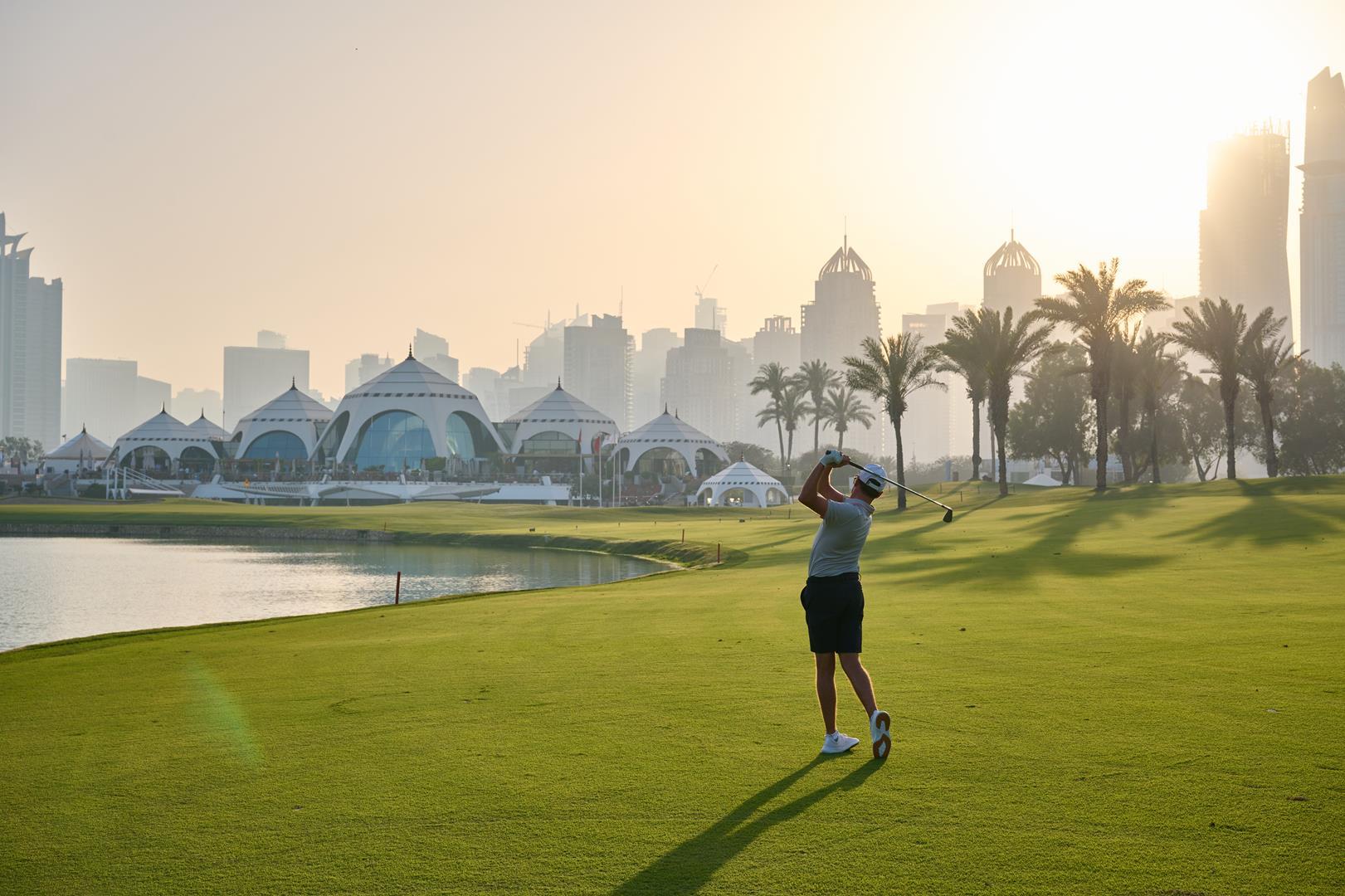 Golfer teeing off with skyscrapers in the background