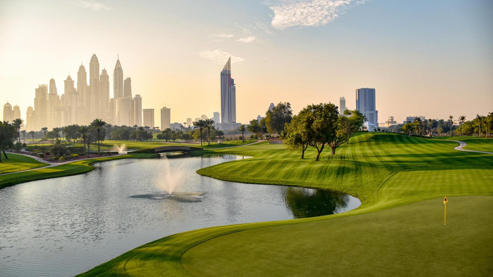 A well maintained fairway leading to a manicured green next to a water hazard featuring a fountain