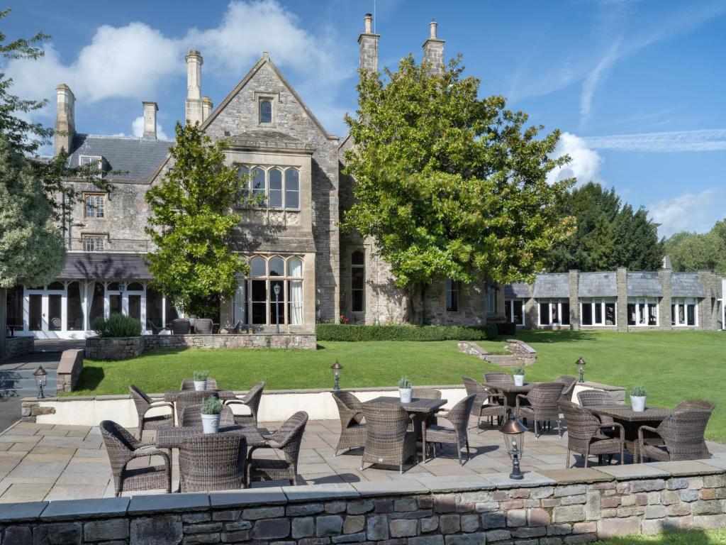 A historic stone building, set in a manicured lawn and trees with seated area
