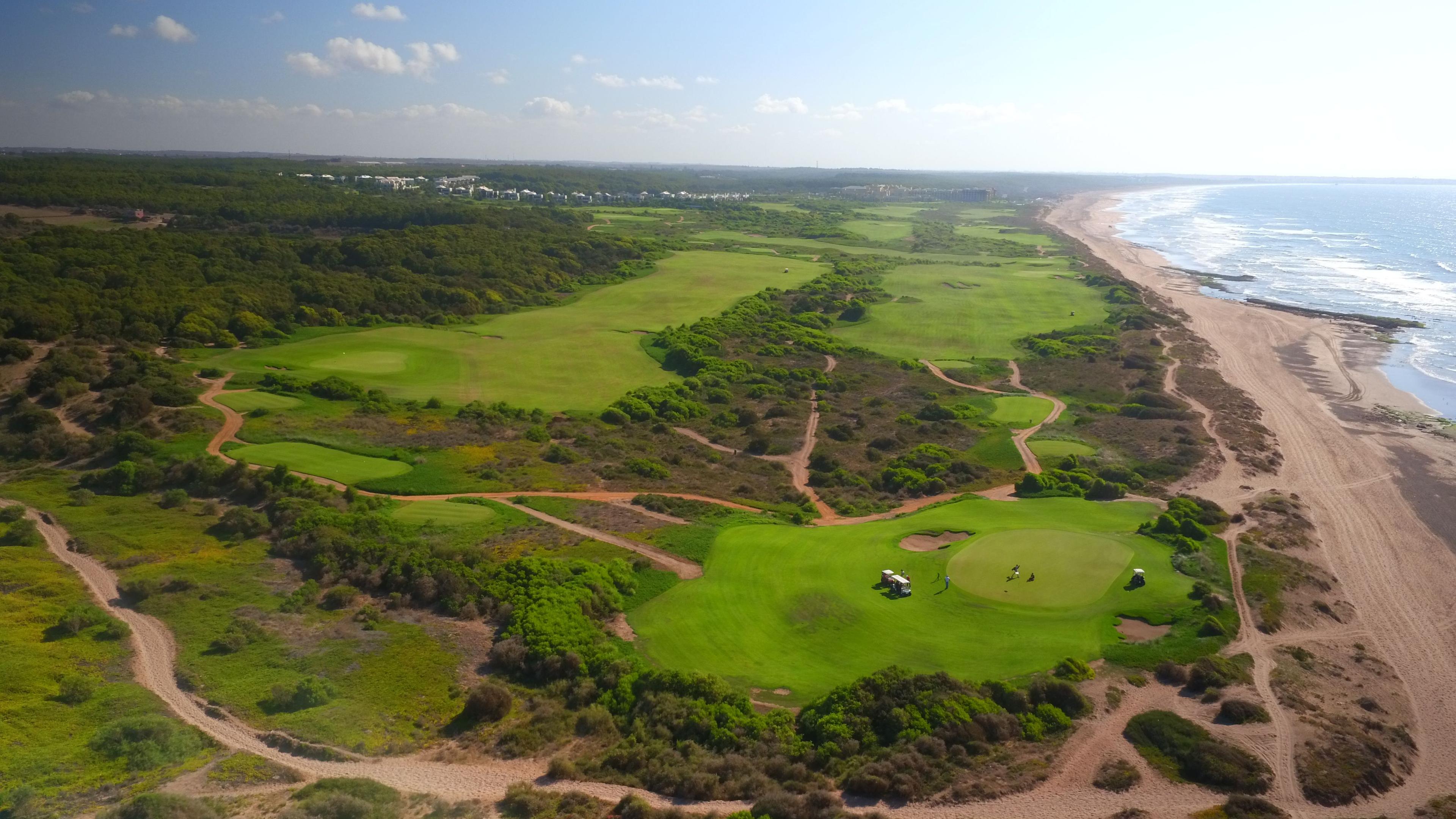 Overhead view of golfers on well maintained green with their buggy parked