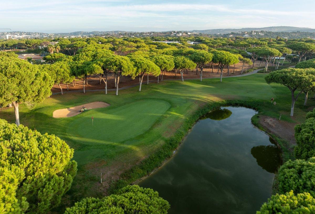 Tree-lined fairway leading to a green with water on the right