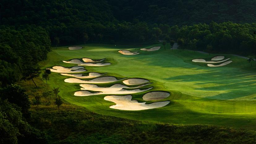 Stunning green course surrounded by dense forest and dramatic bunkers.