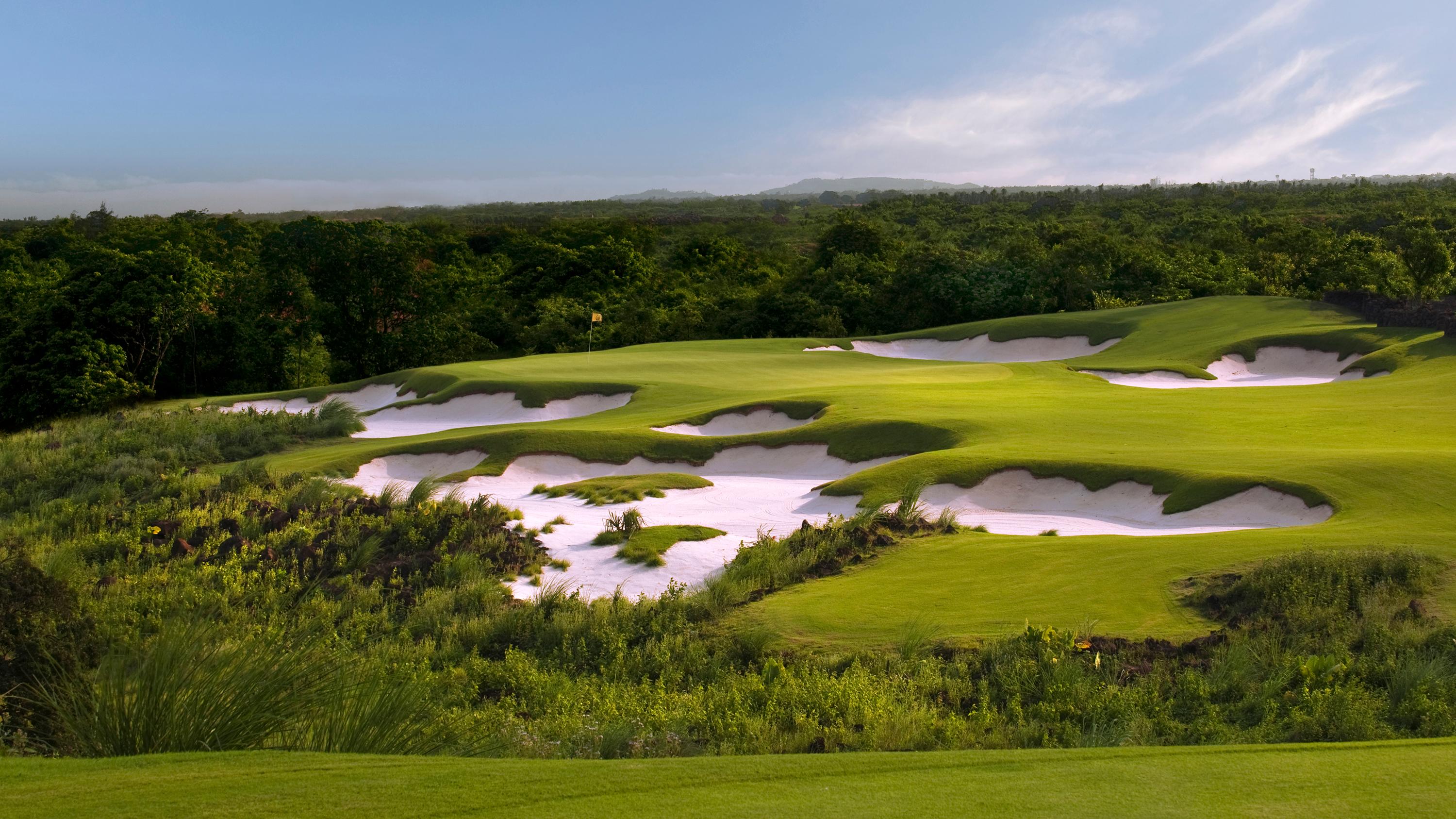 A golf hole with striking white sand bunkers surrounded by dense forest.