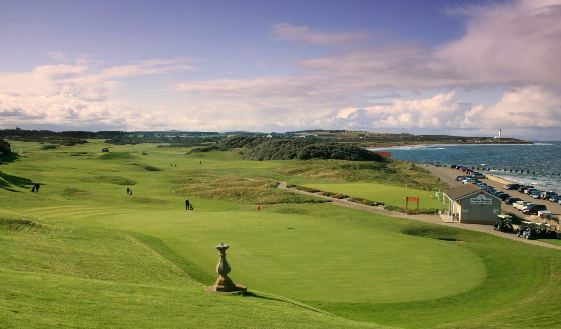 Golfers playing along a coastal links course with ocean views.