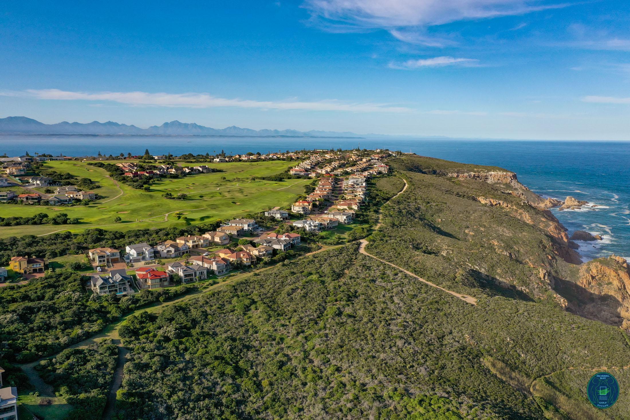 Aerial view of Mossel Bay Golf Club with homes overlooking the ocean.