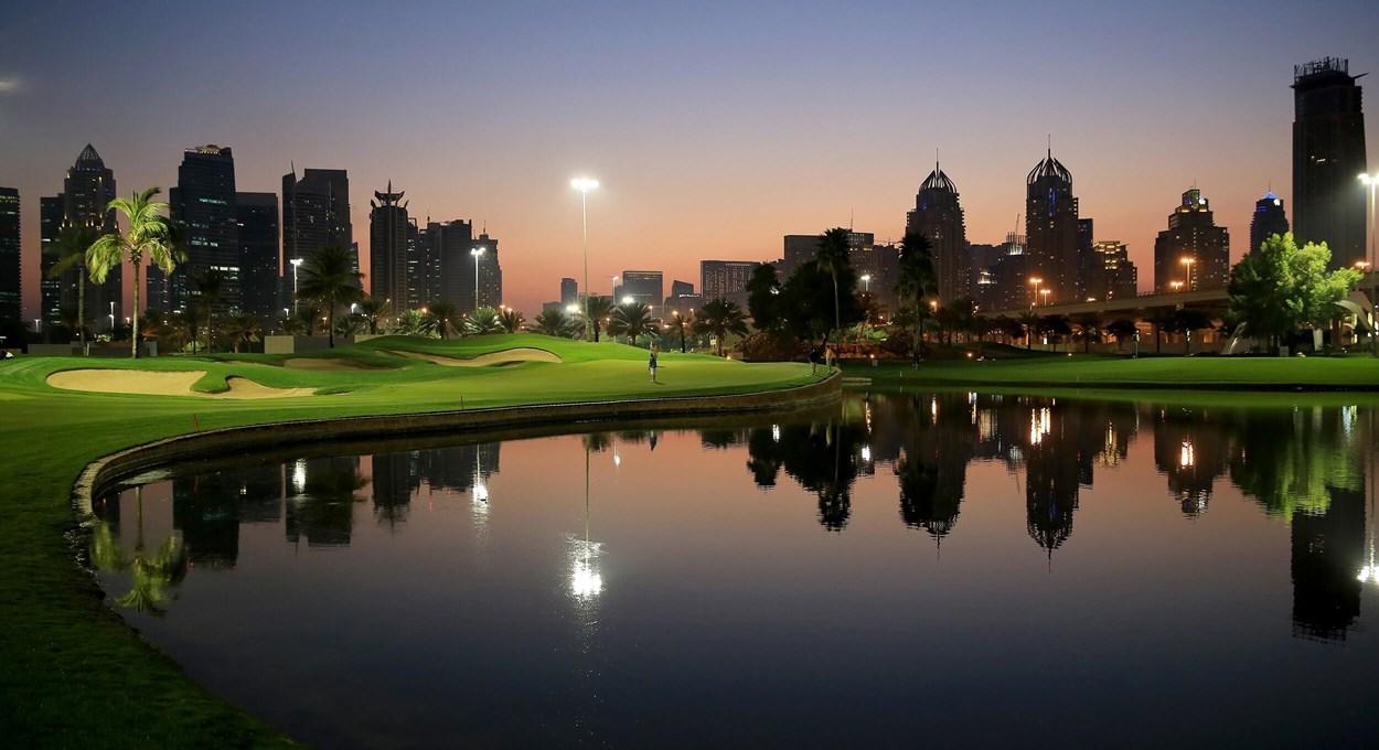 Panoramic view of Night Golf on Emirates Faldo with lights and buildings reflecting off the water hazard