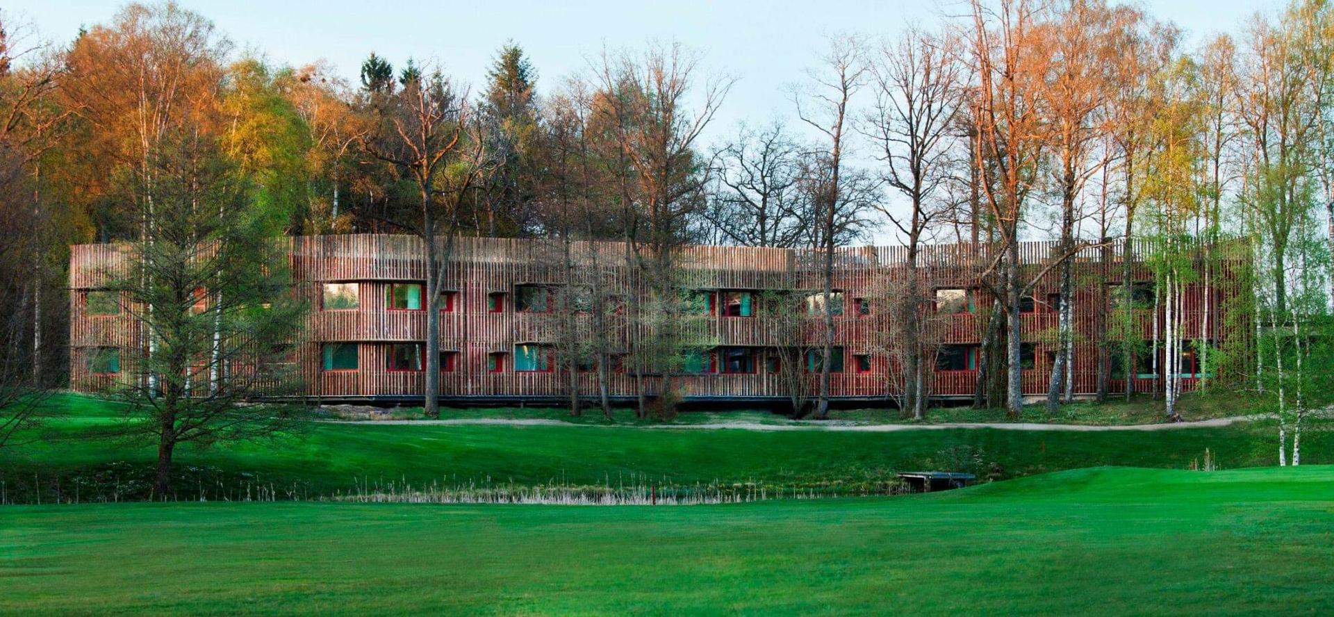 A modern wooden hotel building blending seamlessly with the surrounding forest.