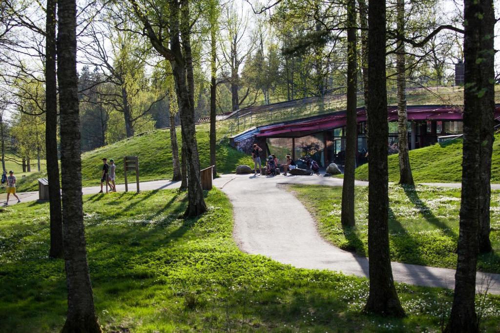 People walking near a unique, nature-blended building surrounded by trees.