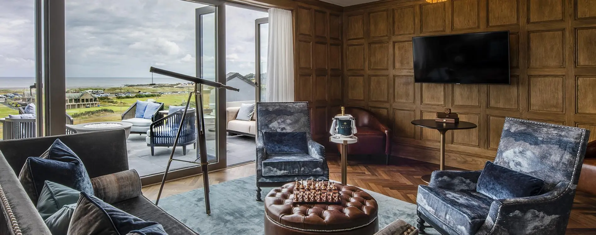 A stylish lounge with a balcony showcasing sweeping golf course and sea views.