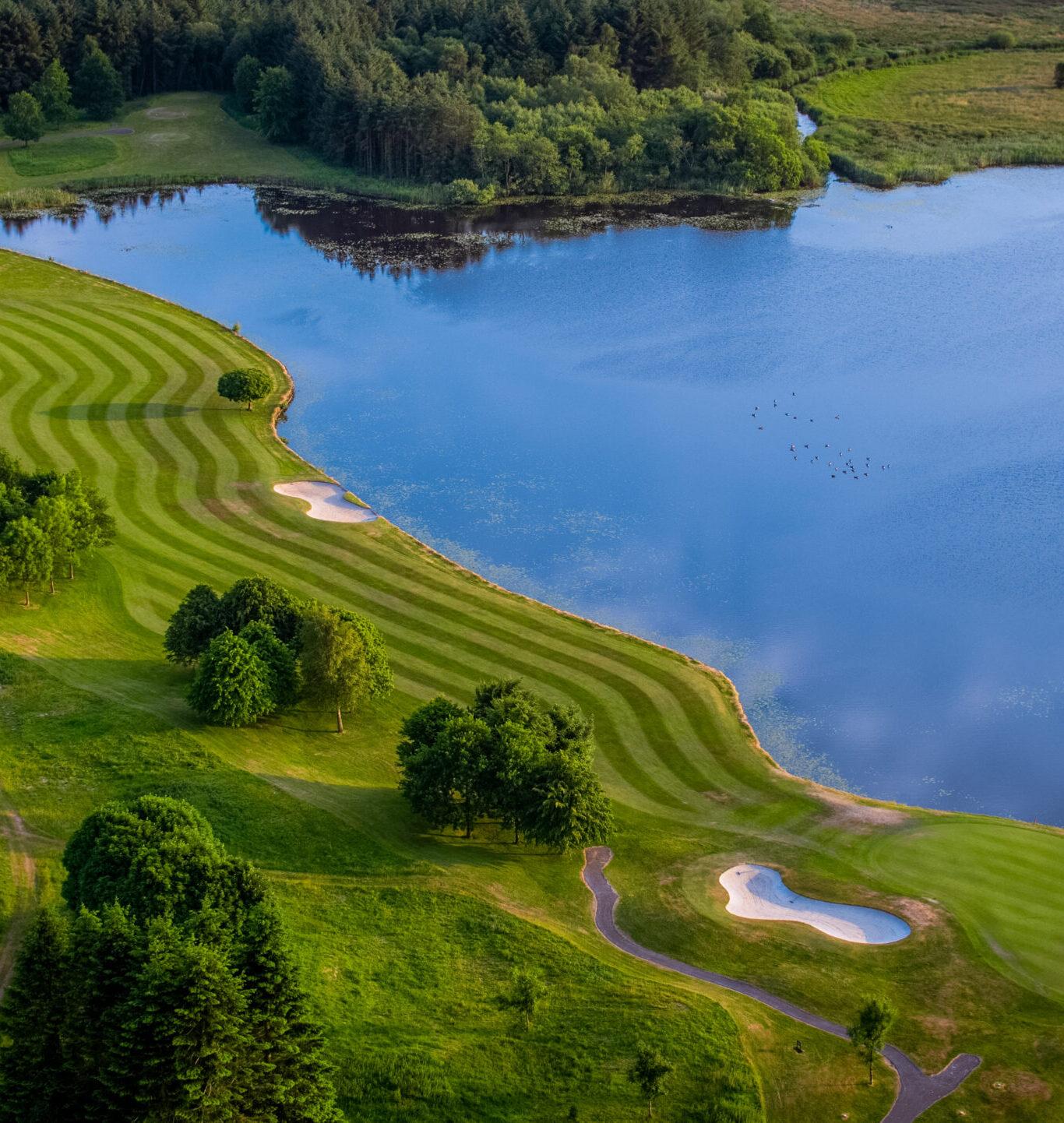 Aerial view of the well-maintained greens at the PGA National Course next to a body of water